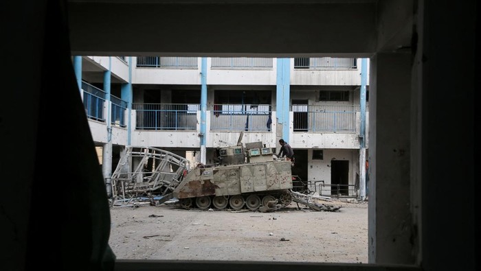 Palestinians look at a damaged Israeli military vehicle left behind by Israeli forces, following a ceasefire between Israel and Hamas, in Rafah in the southern Gaza Strip, January 22, 2025. REUTERS/Hatem Khaled