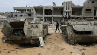 Warga Palestina melihat kendaraan militer Israel yang rusak yang ditinggalkan oleh pasukan Israel, menyusul gencatan senjata antara Israel dan Hamas, di Rafah di Jalur Gaza selatan, 22 Januari 2025.  