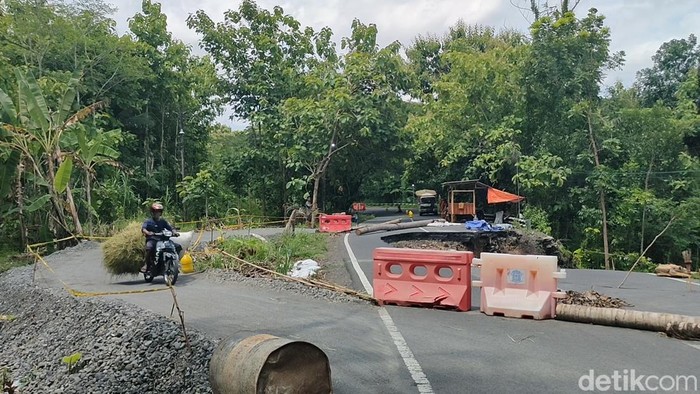 Pengendara melintasi jalan darurat di pinggir jalan Sentolo - Nanggulan yang longsor di Dusun Setan, Kalurahan Wijimulyo, Kapanewon Nanggulan, Kulon Progo, Sabtu (25/1/2025).