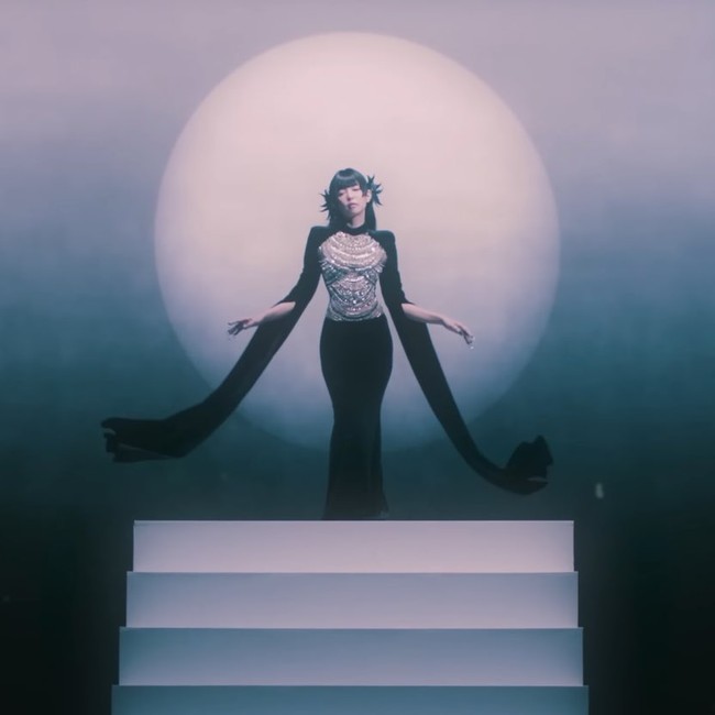 Penggemar semakin penasaran, tak sabar ‘Ruby’ dirilis usai melihat konsep yang disuguhkan. Dalam salah satu adegan, Jennie memakai gaun hitam berbentuk cape rancangan desainer Rusia, YANINA Couture. Bagian tengah gaun berhias payet, memberikan kesan mewah dan elegan. Foto: dok. YouTube JENNIE