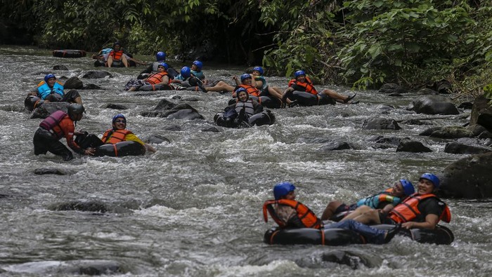 Wisatawan menggunakan ban menyusuri aliran Sungai Cikalumpang saat berwisata alam di Kampoeng 165, Padarincang, Kabupaten Serang, Banten, Sabtu (25/1/2025). Objek wisata alam tersebut menjadi salah satu tujuan wisata yang ramai dikunjungi saat akhir pekan dan liburan dengan menawarkan sejumlah fasilitas seperti area untuk berkemah serta wahana susur sungai menggunakan ban atau river tubing. ANTARA FOTO/Angga Budhiyanto/Spt.