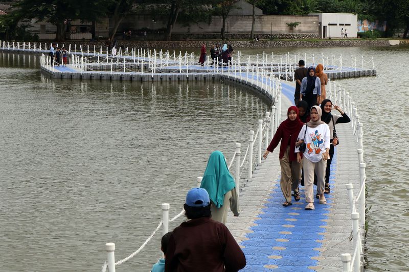 Wisatawan melintas di jembatan apung Situ Rawa Kalong, Depok, Jawa Barat, Sabtu (25/1/2025). Jembatan apung yang dibangun kolaborasi Pemerintah Provinsi Jawa Barat dan Pemkot Depok tersebut menjadi daya tarik bagi warga yang berkunjung memanfaatkan libur akhir pekan, serta libur panjang Isra Miraj Nabi Muhammad dan Tahun Baru Imlek. ANTARA FOTO/Yulius Satria Wijaya/Spt.