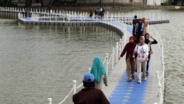 Wisatawan melintas di jembatan apung Situ Rawa Kalong, Depok, Jawa Barat, Sabtu (25/1/2025). Jembatan apung yang dibangun kolaborasi Pemerintah Provinsi Jawa Barat dan Pemkot Depok tersebut menjadi daya tarik bagi warga yang berkunjung memanfaatkan libur akhir pekan, serta libur panjang Isra Miraj Nabi Muhammad dan Tahun Baru Imlek. ANTARA FOTO/Yulius Satria Wijaya/Spt.