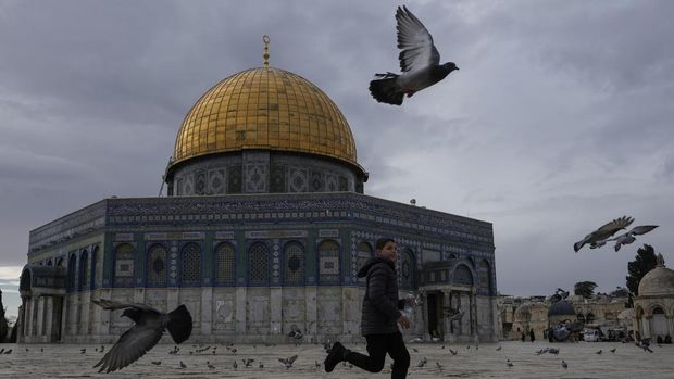 A boy runs amid pigeons flying next to the Dome of Rock Mosque at the Al-Aqsa Mosque compound in Old City of Jerusalem, Monday, Dec. 30, 2024. (AP Photo/Matias Delacroix)