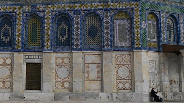 A woman sits next to the Dome of Rock Mosque at the Al-Aqsa Mosque compound in Old City of Jerusalem, Monday, Dec. 30, 2024. (AP Photo/Matias Delacroix)