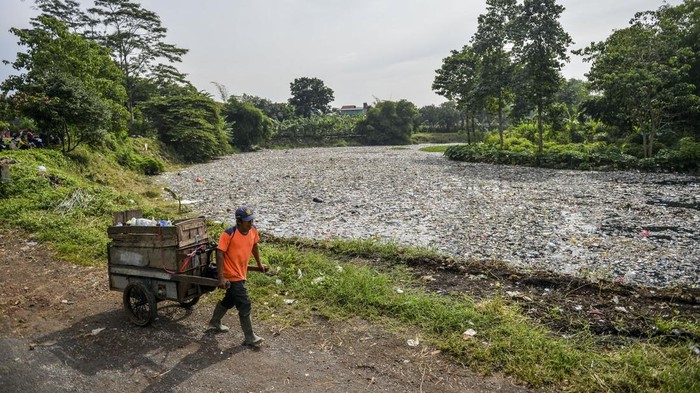 Petugas kebersihan melintas di samping tumpukan sampah yang menumpuk di Sungai Citarum Lama, di Cicukang, Margaasih, Kabupaten Bandung, Jawa Barat, Senin (27/1/2025). Petugas Balai Besar Wilayah Sungai (BBWS) Citarum menyatakan, sampah sepanjang 800 meter dengan lebar sungai 12 meter serta ketinggian mencapai dua meter yang diperkirakan mencapai 19 ton tersebut menumpuk sejak awal Januari 2025 yang saat ini sedang diangkut menggunakan alat berat oleh petugas gabungan. ANTARA FOTO/Raisan Al Farisi/foc.