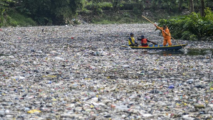 Petugas kebersihan melintas di samping tumpukan sampah yang menumpuk di Sungai Citarum Lama, di Cicukang, Margaasih, Kabupaten Bandung, Jawa Barat, Senin (27/1/2025). Petugas Balai Besar Wilayah Sungai (BBWS) Citarum menyatakan, sampah sepanjang 800 meter dengan lebar sungai 12 meter serta ketinggian mencapai dua meter yang diperkirakan mencapai 19 ton tersebut menumpuk sejak awal Januari 2025 yang saat ini sedang diangkut menggunakan alat berat oleh petugas gabungan. ANTARA FOTO/Raisan Al Farisi/foc.