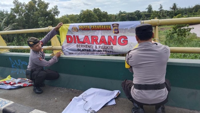 Polisi saat memasang spanduk larangan berhenti dan parkir di Jembatan Srandakan baru, Bantul, Selasa (28/1/2025).