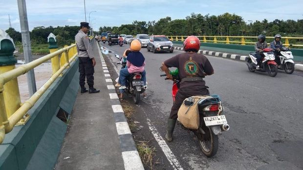 Polisi saat memasang spanduk larangan berhenti dan parkir di Jembatan Srandakan baru, Bantul, Selasa (28/1/2025).