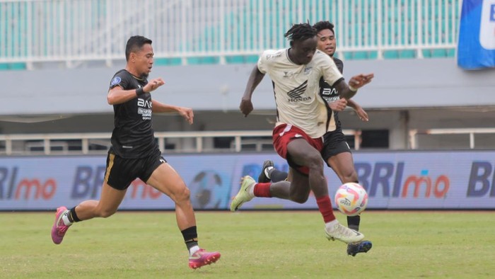 Striker PSM Makassar Balotelli beradu sprint dengan bek Dewa United Reva Adi Utama dalam laga Liga 1 2024/2025 di Stadion Pakansari.