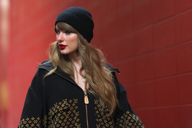 Taylor Swift tampak memakai jaket hitam dengan motif monogram ‘LV’ berwarna emas yang menghiasi bagian depan hingga lengan, seharga US$5,000 atau sekitar Rp 81 juta. Foto: Getty Images/Aaron M. Sprecher