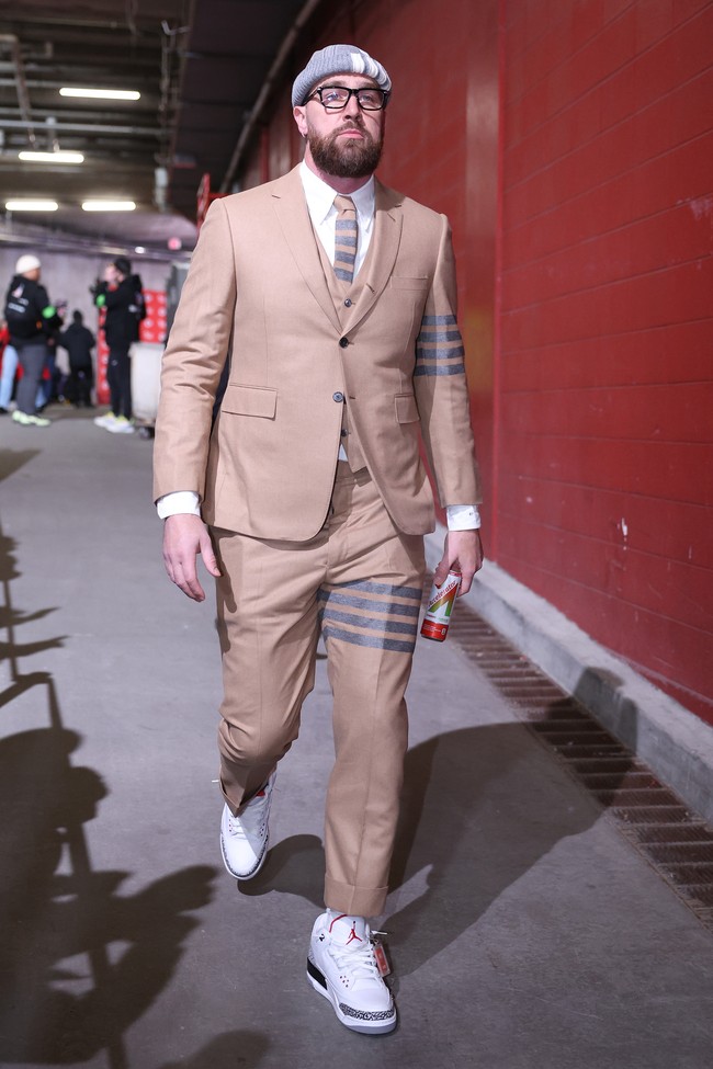 Melengkapi gaya serba Thom Browne, Travis juga memakai topi beanie abu-abu dengan aksen empat garis yang jadi ikon brand asal AS itu. Foto: Getty Images/David Eulitt