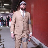 Melengkapi gaya serba Thom Browne, Travis juga memakai topi beanie abu-abu dengan aksen empat garis yang jadi ikon brand asal AS itu. Foto: Getty Images/David Eulitt