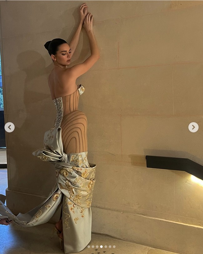 Gaun Kendall Jenner yang berwarna beige menonjolkan desain sculptural dengan detail pinggul yang menonjol dan motif floral yang menghiasi bagian bust dan hemline. Bagian belakang gaun ini juga mencuri perhatian dengan detail korset yang dramatis dan pita besar yang memberikan kesan megah. Foto: Dok. Instagram