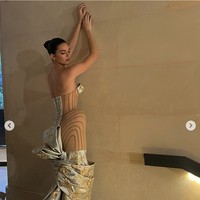 Gaun Kendall Jenner yang berwarna beige menonjolkan desain sculptural dengan detail pinggul yang menonjol dan motif floral yang menghiasi bagian bust dan hemline. Bagian belakang gaun ini juga mencuri perhatian dengan detail korset yang dramatis dan pita besar yang memberikan kesan megah. Foto: Dok. Instagram