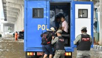 Petugas Satpol PP membantu pekerja melintasi banjir menggunakan truk.