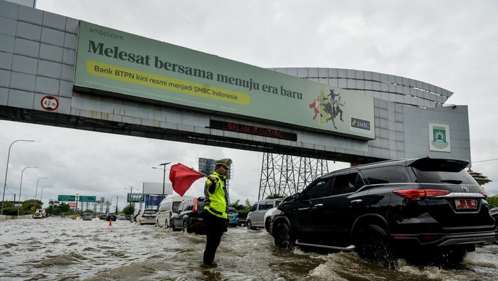 Polisi mengatur lalu lintas kendaraan saat banjir di Jalan Tol Sedyatmo, Cengkareng, Jakarta, Rabu (29/1/2025). Jalan tol yang merupakan akses menuju Bandara Soekarno-Hatta tersebut terendam banjir setinggi 20-30 sentimeter akibat tingginya intensitas hujan. ANTARA FOTO/Putra M. Akbar/gp/tom.
