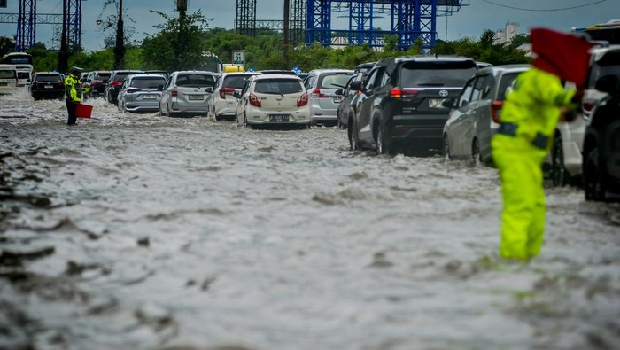 Polisi mengatur lalu lintas kendaraan saat banjir di Jalan Tol Sedyatmo, Cengkareng, Jakarta, Rabu (29/1/2025). Jalan tol yang merupakan akses menuju Bandara Soekarno-Hatta tersebut terendam banjir setinggi 20-30 sentimeter akibat tingginya intensitas hujan. ANTARA FOTO/Putra M. Akbar/gp/tom.