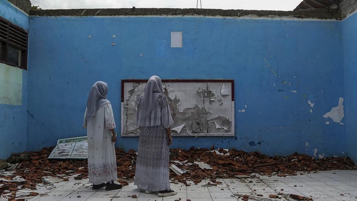 Tiga siswi berjalan di dekat ruang kelas yang rusak di SMP Negeri 2 Cikeusal, Kabupaten Serang, Banten, Kamis (30/1/2025). Pihak sekolah mengatakan, sebanyak tiga ruang kelas mengalami kerusakan parah sejak Februari 2024 sementara satu ruang kelas lainnya ambruk pada 18 Januari 2025 akibat kondisi bangunan tua dan faktor cuaca sehingga kegiatan belajar mengajar harus dipindahkan ke ruangan lain yang kondisi bangunannya masih layak. ANTARA FOTO/Angga Budhiyanto/nym.