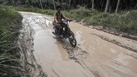 Pengendara sepeda motor melintasi jalan rusak di Panca Mulya, Muaro Jambi, Jambi, Kamis (30/1/2025).   