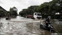 Sejumlah warga menerobos banjir di kawasan Jalan Raya Cakung Cilincing, Jakarta Utara, Kamis (30/1/2024).   