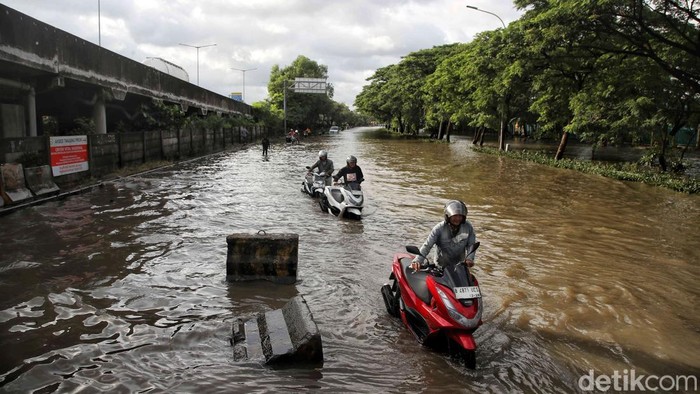 Sejumlah warga menerobos banjir di kawasan Jalan Raya Cakung Cilincing, Jakarta Utara, Kamis (30/1/2024).