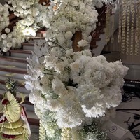 Tangga utama rumah tampak dipenuhi dengan bunga-bunga berwarna putih. Tangga tersebut menjadi latar belakang dari tempat ijab kabul Uta dan Andie. Perpaduan nuansa Bali terlihat dalam beberapa dekorasi yang turut menghiasi. Foto: Instagram/@bimo_singgih