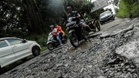 Pengendara yang melintas melambatkan lajunya supaya tidak terperosok.   