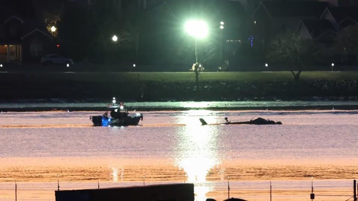 Rescuers on a boat work next to the wreckage of a Black Hawk helicopter, as the sun rises, at the site of the crash after it collided with the American Eagle flight 5342, which was approaching Reagan Washington National Airport, and crashed into the Potomac River, outside Washington, U.S., January 30, 2025. REUTERS/Kevin Lamarque TPX IMAGES OF THE DAY Purchase Licensing Rights