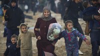 Para pria, wanita, dan anak-anak yang mengungsi berjalan kaki sambil membawa barang-barang mereka. Banyak dari mereka kehilangan anggota keluarga dan rumah mereka hancur. (AP Photo/Abdel Kareem Hana)