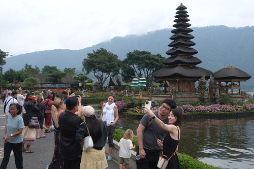 Wisatawan mancanegara berswafoto dengan latar belakang pura di objek wisata Ulun Danu Beratan, Tabanan, Bali, Jumat (31/1/2025). Badan Pusat Statistik (BPS) Provinsi Bali mencatat perekonomian Bali tumbuh 5,43 persen secara tahunan didorong oleh peningkatan transaksi keuangan dan kenaikan kunjungan wisatawan nusantara maupun mancanegara. ANTARA FOTO/Nyoman Hendra Wibowo/foc.