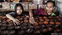 Dua pekerja sedang meyusun kue keranjang yang sudah matang dan siap dipasarkan.