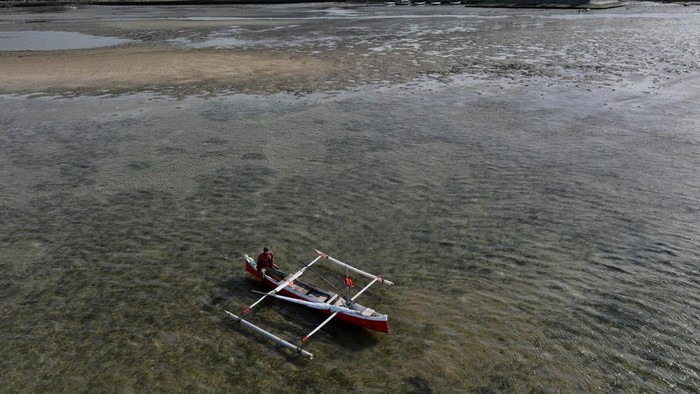 Foto udara nelayan berada di samping perahunya di laut Pantai Mandra yang mengalami pendangkalan di Kolaka, Sulawesi Tenggara, Jumat (31/1/2025). Muatan sedimen dari aliran Sungai Baladente menyebabkan pendangkalan di Pantai Madra. ANTARA FOTO/Jojon/foc.