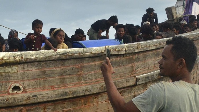 Puluhan Migran Rohingya Kembali Mendarat di Aceh Timur Local residents examine a boat carrying Rohingya refugees stranded on a beach in Peureulak, Aceh province, Indonesia, Wednesday, Jan. 29, 2025. (AP Photo/Husna Mura)