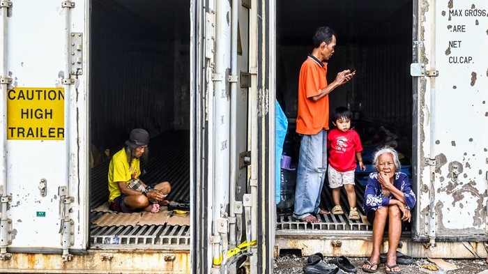 Pengungsi menggendong anaknya di dalam kontainer kosong di Rorotan, Jakarta, Jumat (31/1/2025). Warga Kampung Sepatan, RT 18/05, Rorotan, Cilincing terpaksa mengungsi ke kontainer kosong setelah kediamannya terendam banjir setinggi satu meter. ANTARA FOTO/Rivan Awal Lingga/nz