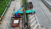 Pekerja memperbaiki papan petunjuk arah yang roboh akibat ditabrak sebuah bus milik Brimob Polri yang mengangkut rombongan siswa SMA 1 Porong Sidoarjo di Exit Tol Purwodadi, Pasuruan, Jawa Timur, Sabtu (1/2/2025).
