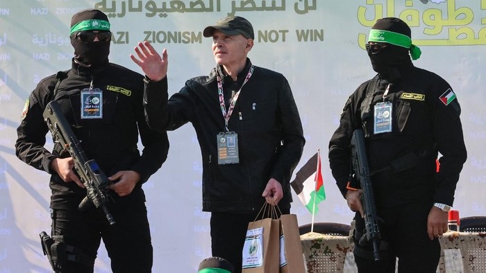 Palestinian militant group Hamas fighters escort American-Israeli hostage Keith Siegel on a stage before handing him over to a Red Cross team in Gaza City on February 1, 2025, as part of the fourth hostage-prisoner exchange. (Photo by Omar AL-QATTAA / AFP)