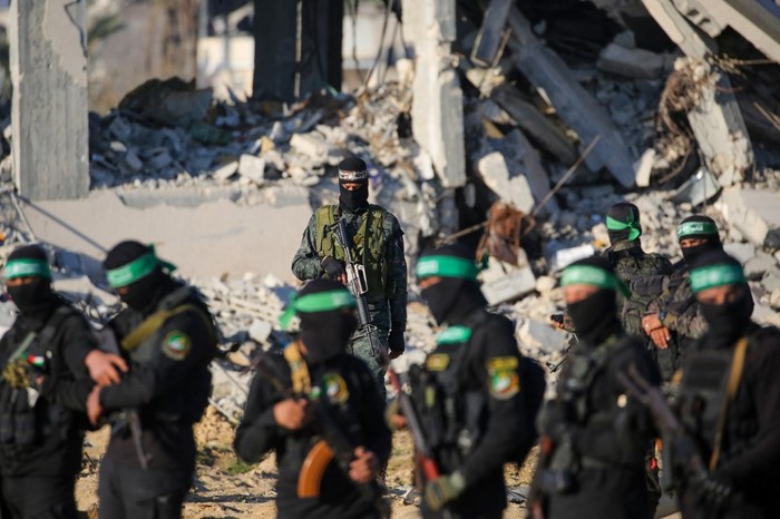 Palestinian militant group Hamas fighters secure an area before handing over two Israeli hostages to a Red Cross team in Khan Yunis on February 1, 2025, as part of fourth hostage-prisoner exchange. The Israeli military said the two freed hostages had now crossed into Israeli territory after they were released by Hamas on February 1. (Photo by Eyad BABA / AFP)