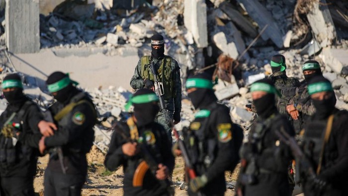 Palestinian militant group Hamas fighters secure an area before handing over two Israeli hostages to a Red Cross team in Khan Yunis on February 1, 2025, as part of fourth hostage-prisoner exchange. The Israeli military said the two freed hostages had now crossed into Israeli territory after they were released by Hamas on February 1. (Photo by Eyad BABA / AFP)