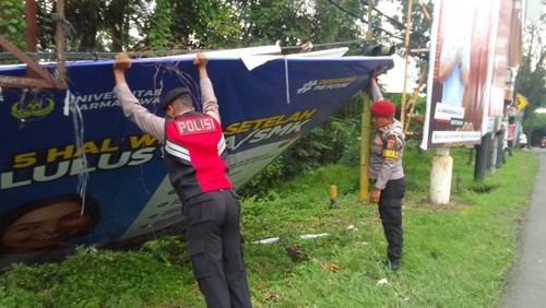 Polisi memindahkan baliho yang menimpa pengendara sepeda motor di Jalan Bypass Ir Soekarno, Tabanan pada Sabtu (1/2/2025). (Polres Tabanan)