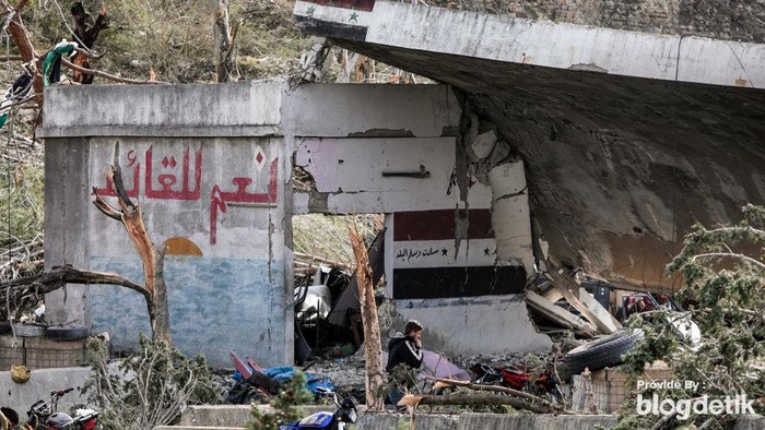 People inspect a destroyed Syrian army bunker at the site of a weapons depot that was hit by overnight Israeli bombardment on the outskirts of the village of Bmalkah in the countryside of Tartus in western Syria on December 16, 2024. A Syrian bunker complex outside the port of Tartus was ablaze and rocked by explosions on December 16 just hours after what the UK-based Syrian Observatory for Human Rights and local residents said was an intense wave of Israeli air strikes. (Photo by Bakr ALKASEM / AFP)