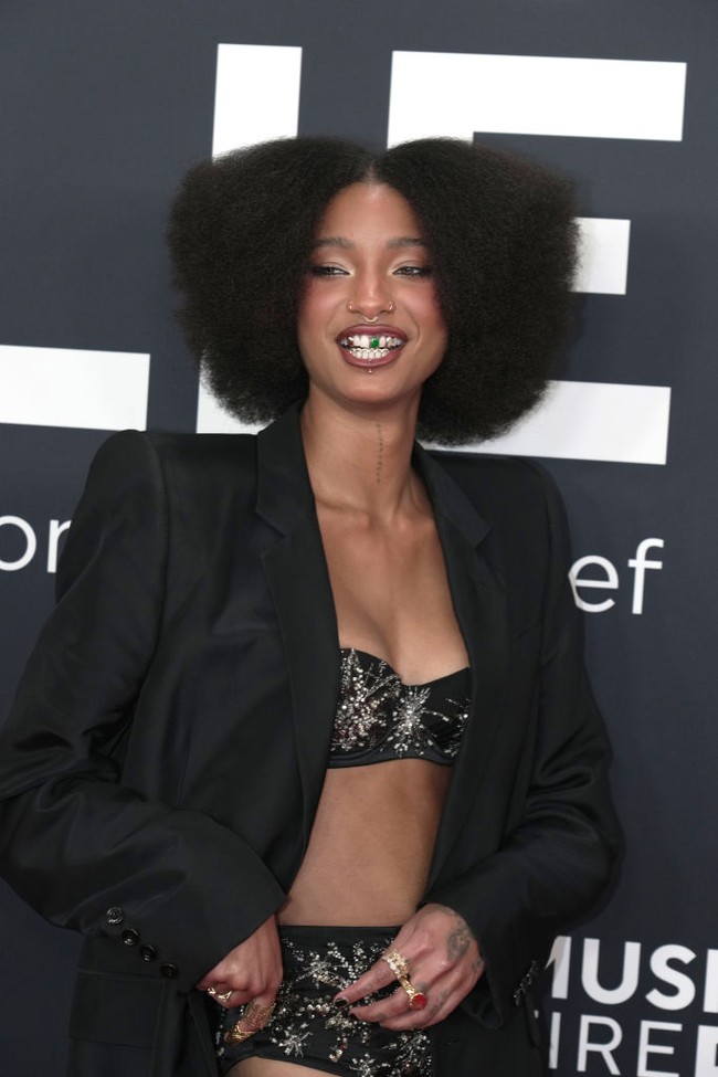 Tak hanya outfit, Willow juga memaksimalkan penampilannya dengan platform sandals berhiaskan kristal, tumpukan cincin, serta grill gigi metalik dengan satu aksen hijau yang menarik perhatian. Foto: Getty Images