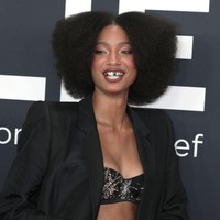 Tak hanya outfit, Willow juga memaksimalkan penampilannya dengan platform sandals berhiaskan kristal, tumpukan cincin, serta grill gigi metalik dengan satu aksen hijau yang menarik perhatian. Foto: Getty Images