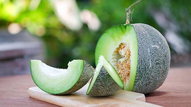 Fresh melon sliced Place on a wooden cutting board on a wooden table with beautiful natural blurred background.