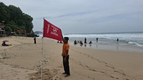 Pemasangan bendera berwarna merah dengan tulisan peringatan bermain di area palung pantai Gunungkidul. Foto diunggah Senin (3/2/2025).