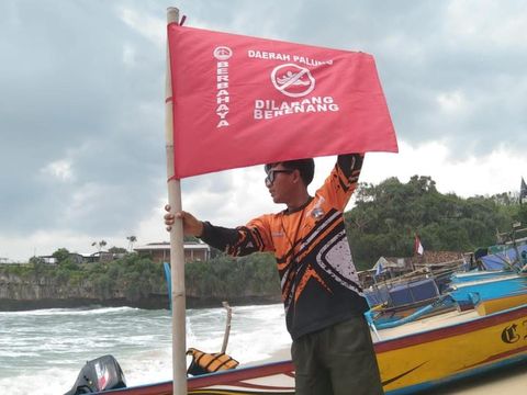 Pemasangan bendera berwarna merah dengan tulisan peringatan bermain di area palung pantai Gunungkidul. Foto diunggah Senin (3/2/2025).