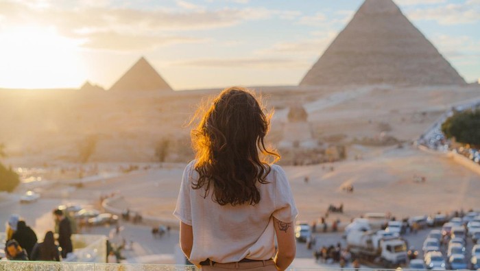 Young Caucasian woman standing on the  terrace on the  background of Giza pyramids