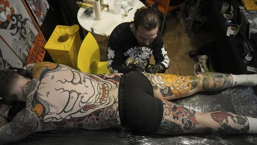 A man with a tattoo on his chest takes part in a contest during a tattoo convention, in Paris, Sunday, Feb. 2, 2025. (AP Photo/Thibault Camus)
