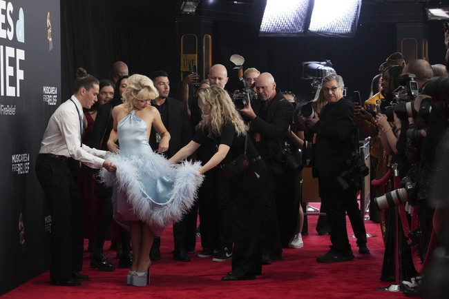 Sabrina memakai gaun halter biru muda yang hadir dengan rok peplum panjang. Penyanyi 25 tahun itu sampai harus dibantu dua orang staff Grammy Awards untuk berpose di karpet merah, karena gaunnya yang panjangnya menyapu lantai. Foto: Jordan Strauss/Invision/AP