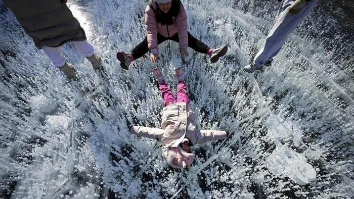 A woman has fun with a child on a frozen lake at a mountain scenic area during a week-long Chinese New Year holiday, in Miyun, north of Beijing on Sunday, Feb. 2, 2025. (AP Photo/Andy Wong)